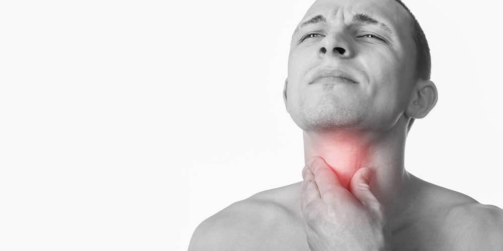 Junger man mit Halsschmerzen fässt sich an den Hals