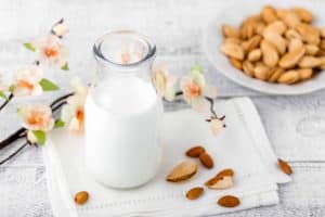 Glas Milch auf einem Tisch mit einer Schale Mandeln