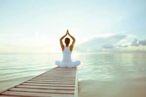 Junge Frau auf einem Steg am See mach Yoga Übungen