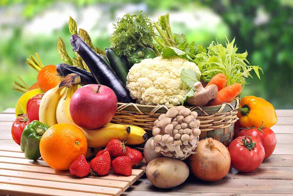 Korb auf einem Holztisch mit Obst und Gemüse