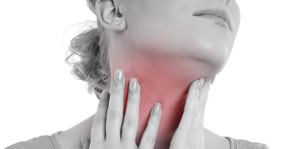 Frau mit Halsschmerzen fasst sich an den Hals
