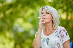 Altere Frau raucht eine Zigarette