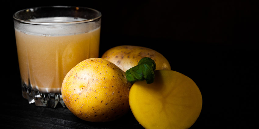 glass of potato juice on dark wooden background with copy space.